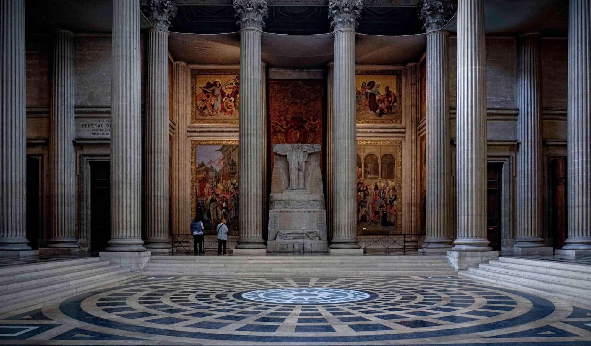 The interior of the Pantheon with a Roman columns, frescoes and blue and grey stone floor.