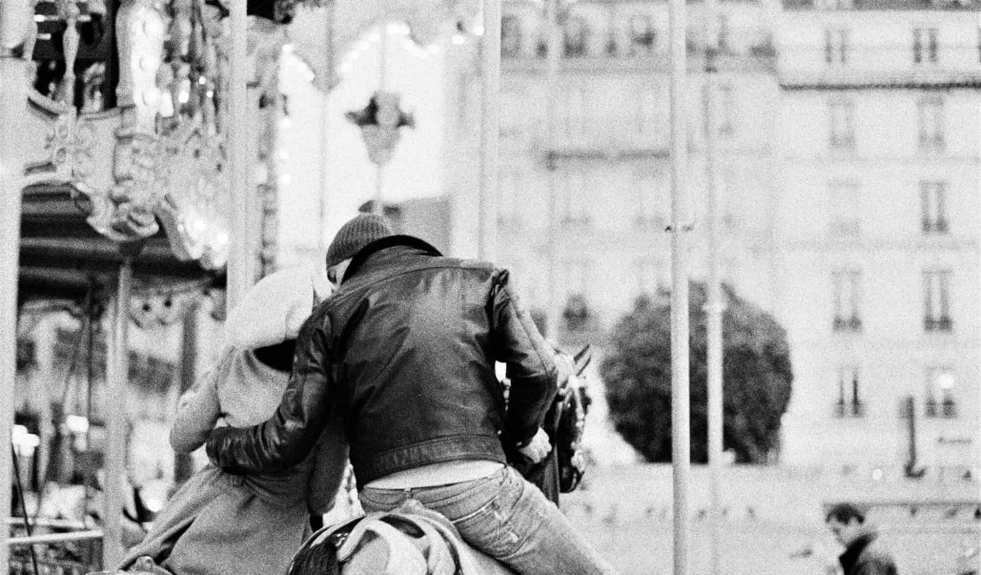 Couple in each others arms kissing in Paris pictured in black and white.