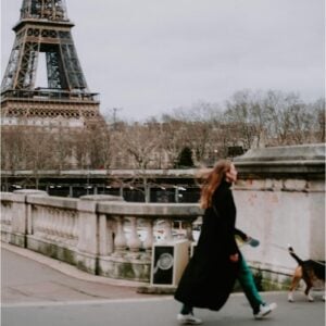 Girl walking a dog in front of the Eiffel Tower, Paris