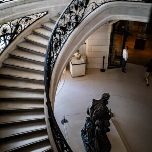 The staircase at the Petit Palais in Paris with wrought-iron railings and a sculpture at the bottom