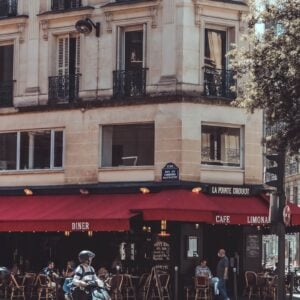 pessoas andando em uma rua parisiense perto de um café em um dia de verão.