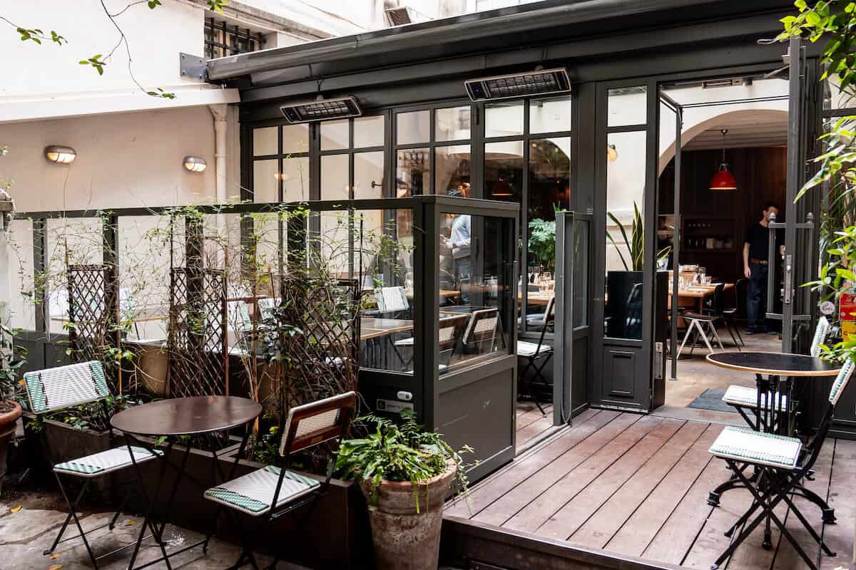 The courtyard seating are of Jaja restaurant in the Marais, with a black frame and wooden floors.