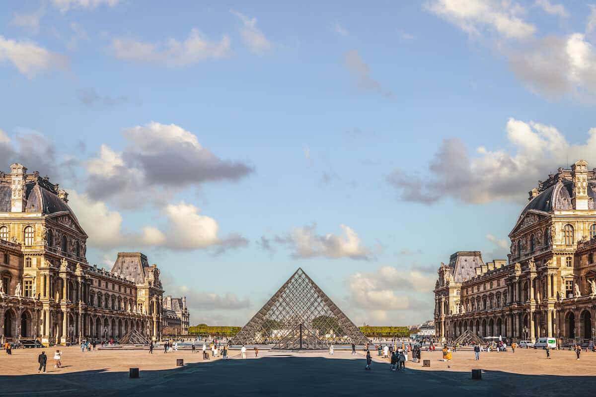 The Pyramid of the Louvre on a partly cloudy day.