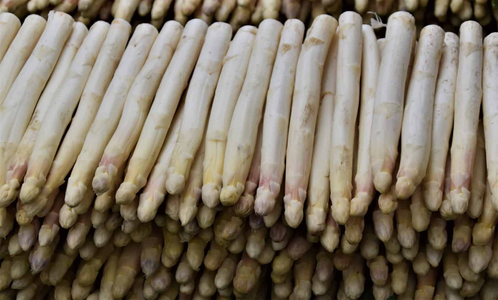 A stack of white asparagus in an open air market.