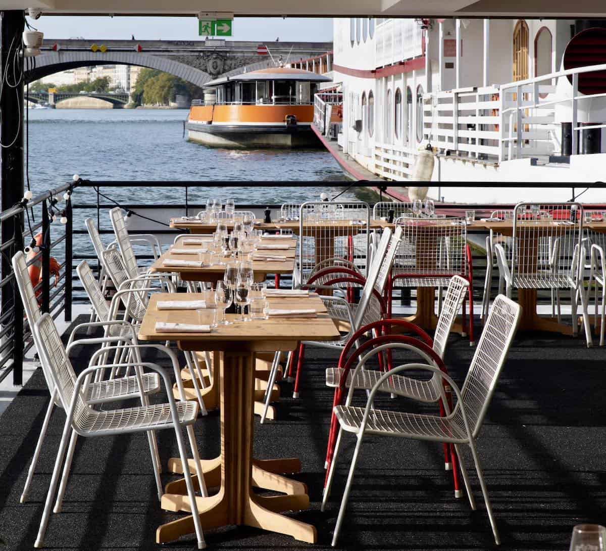 The waterside terrace at Facette restaurant with a moored boat in the background.