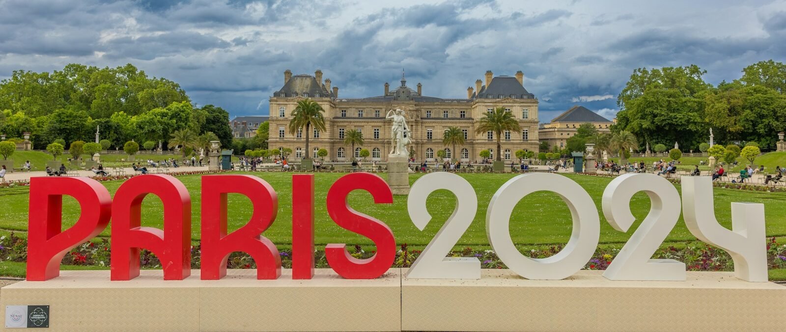 A large red and white sign that says Paris 2024 in front of a building.