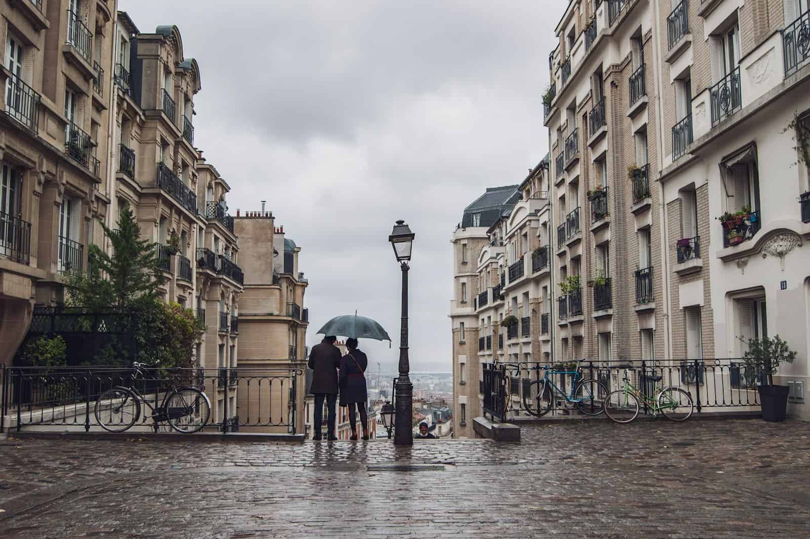 Um casal caminhando pela rua durante um dia chuvoso em Paris.