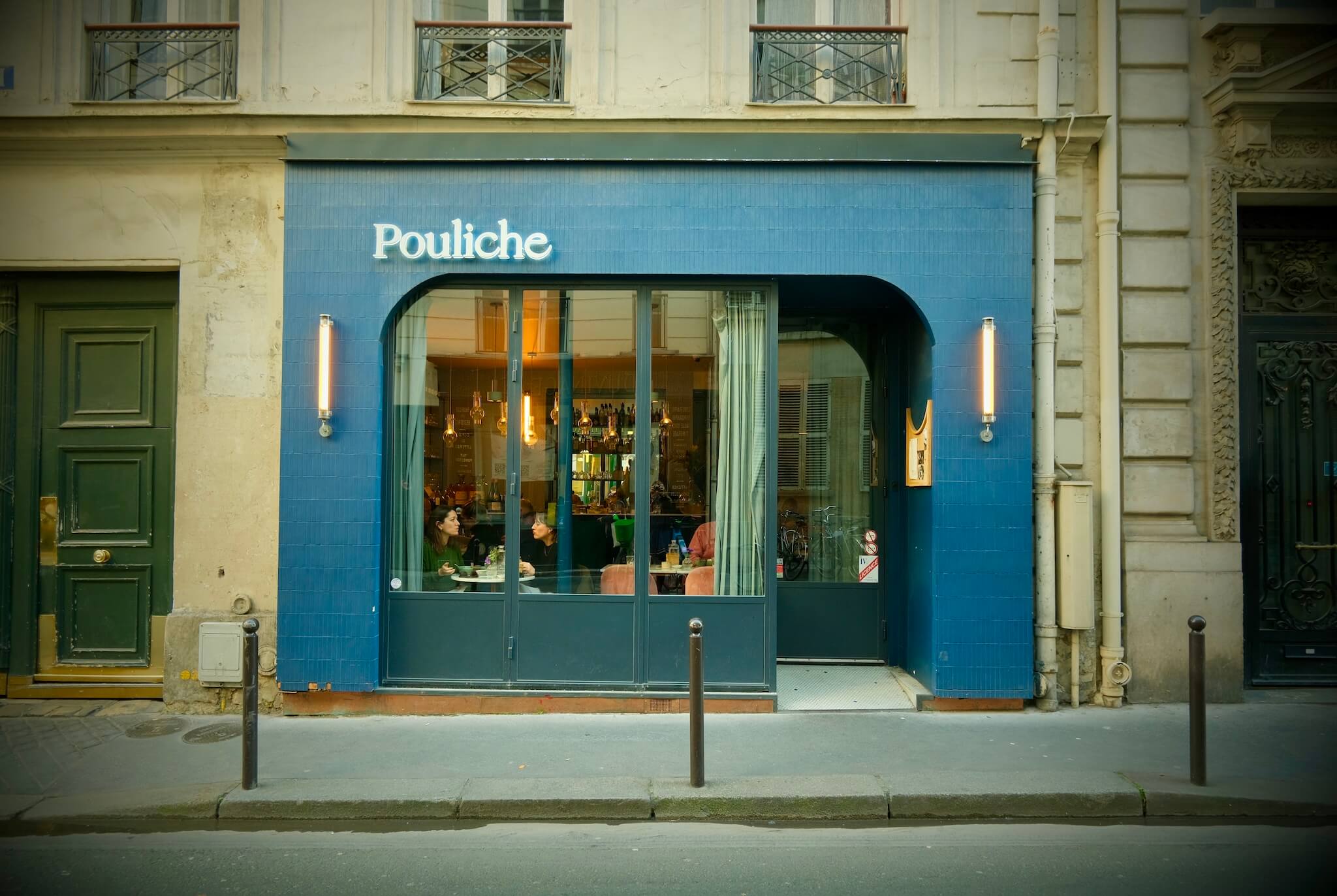 Exterior shot of Pouliche, painted blue with 2 cylindrical light on either side.