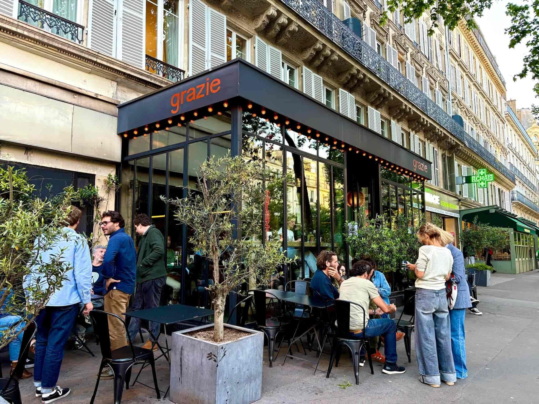 Exterior of Gracie, with a black awning and people sitting out front.