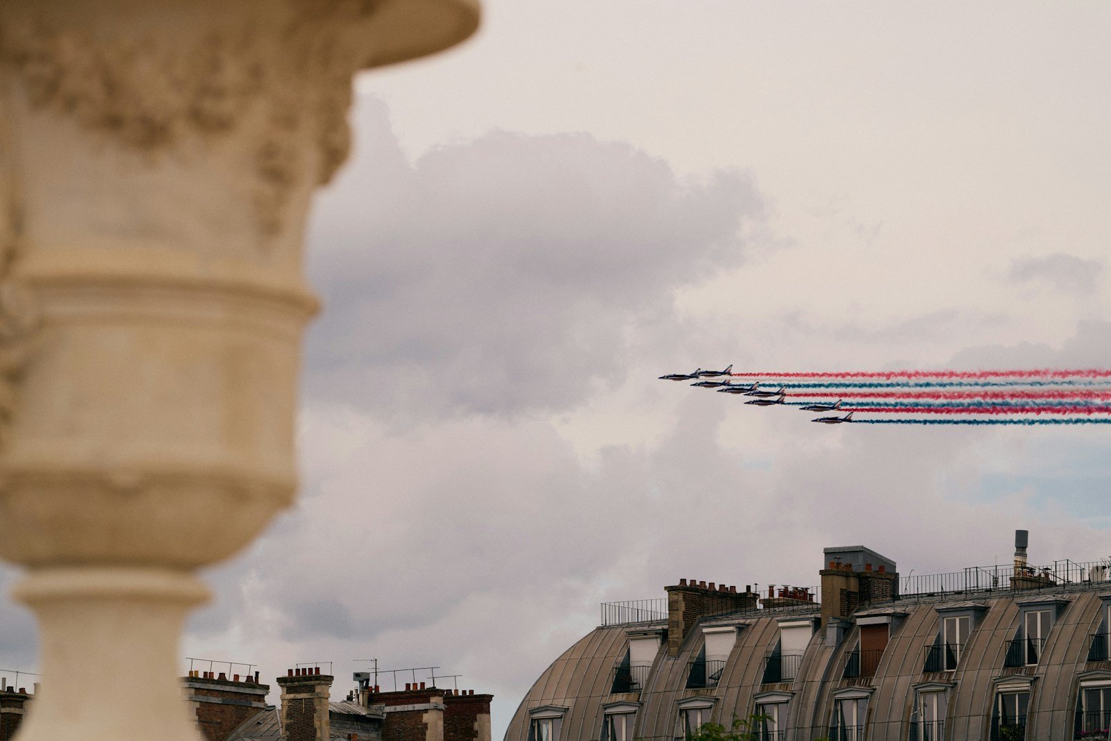 A plane flying over a city next to tall buildings.