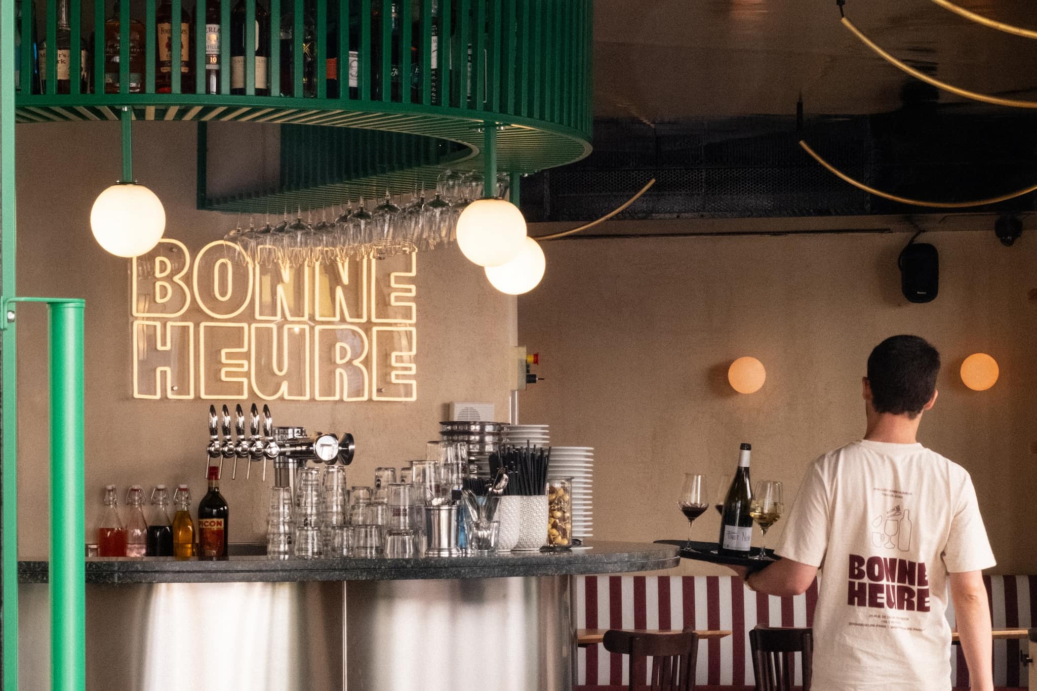 Bonne Heure restaurant interior - a waiter carries a tray of wine and glasses by the bar.