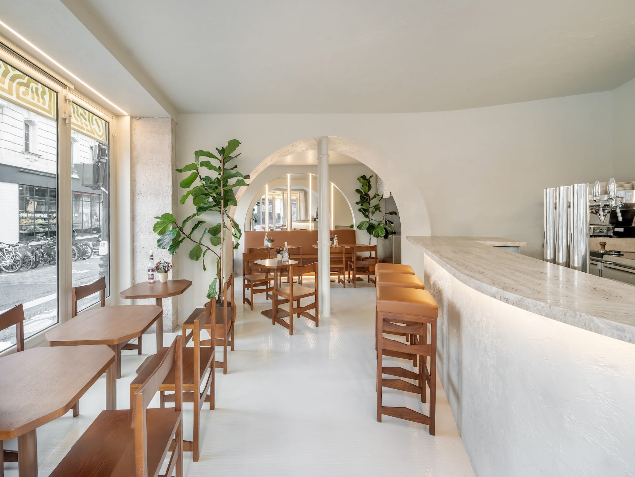 Carlota Paris bright restaurant interior with a bar, tables and plants.