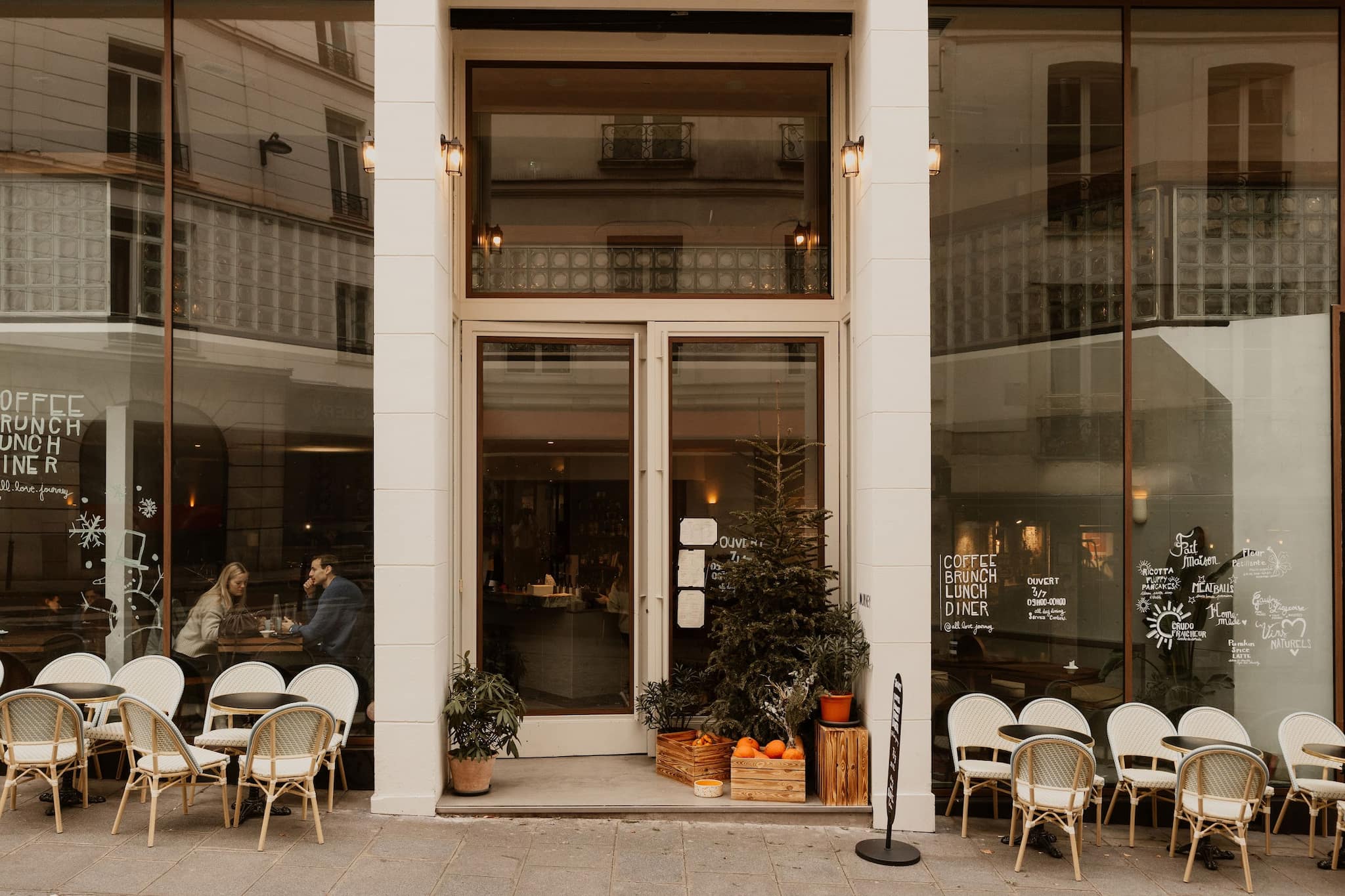 Exterior of Journey restaurant Paris, glass building with tables and chairs outside.