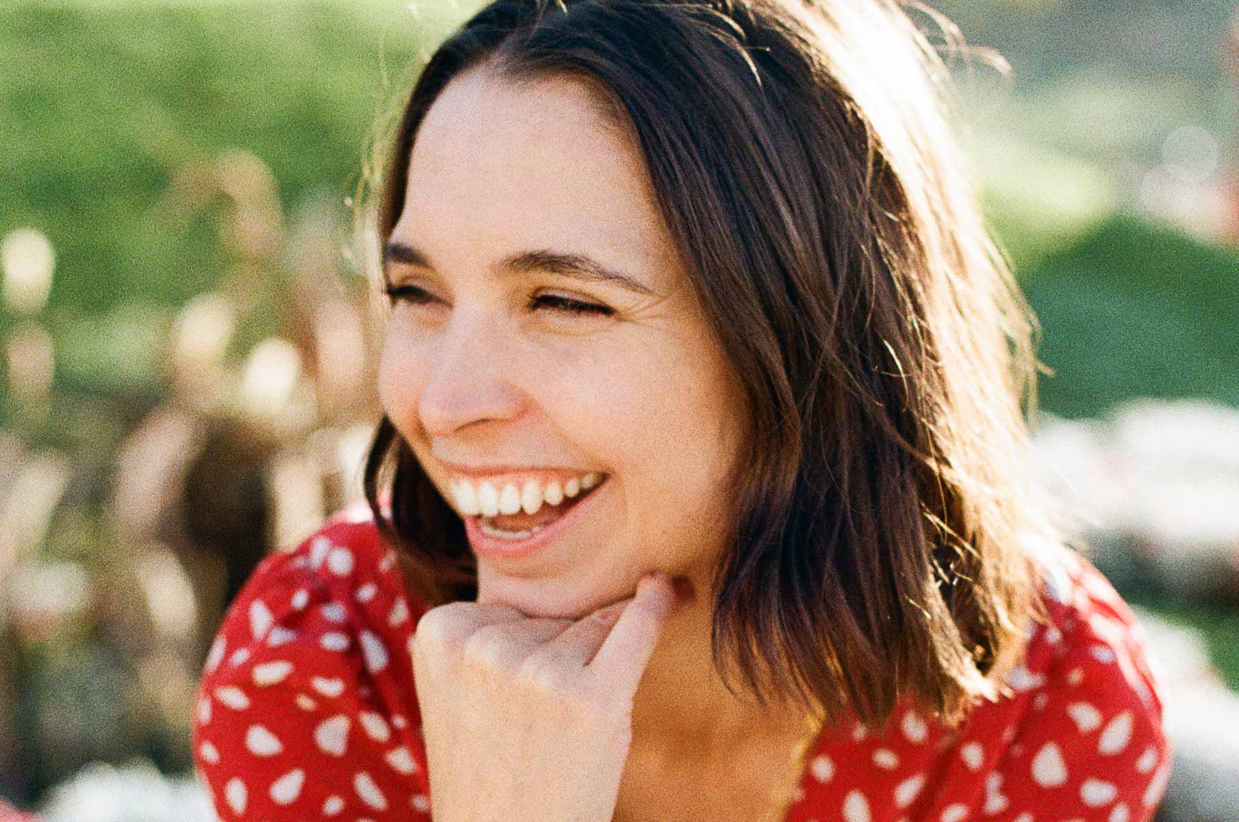 Paris photographer Katie Donnelly smiling on a sunny day wearing a red dress.