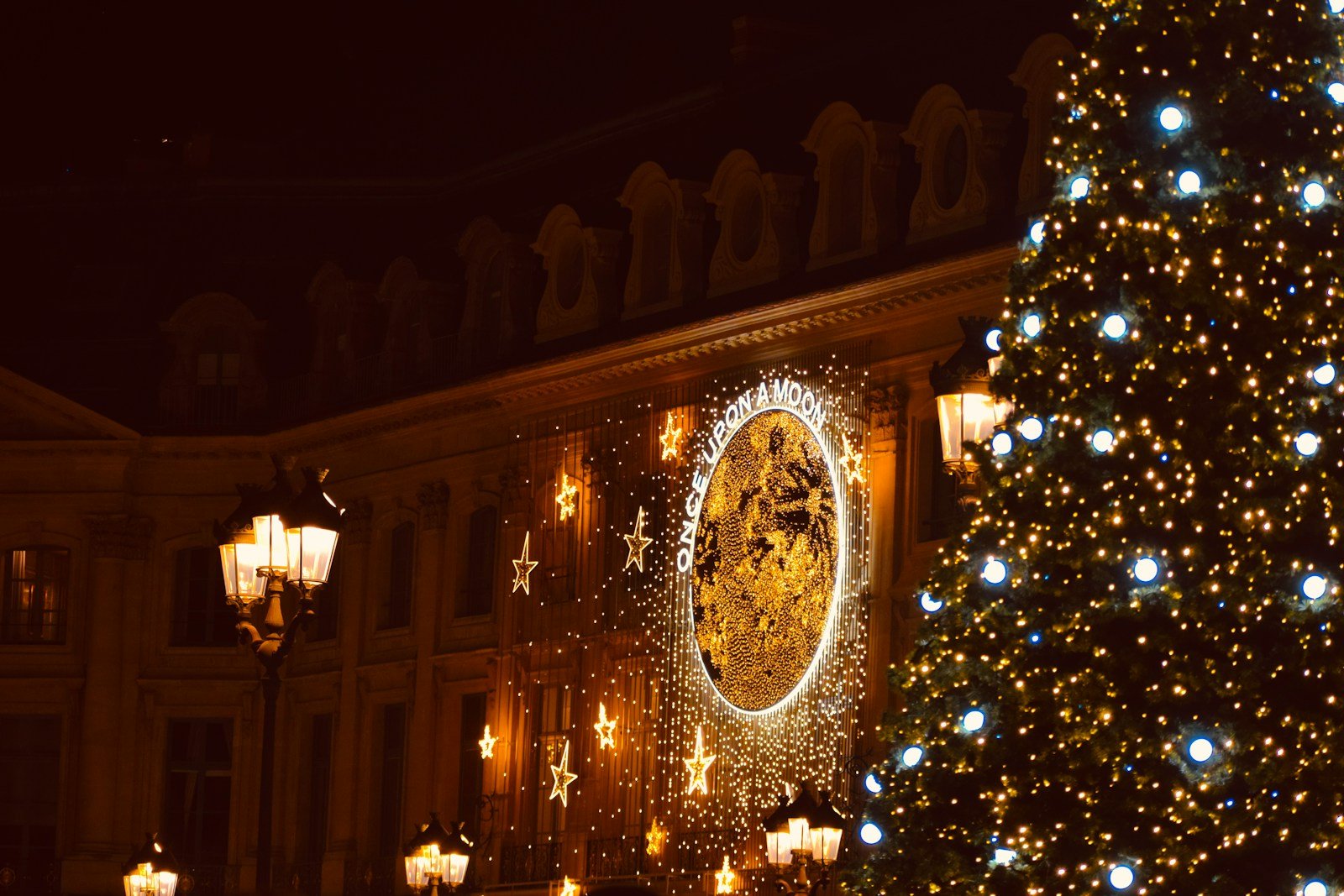 a lit christmas tree in front of a building in Paris.