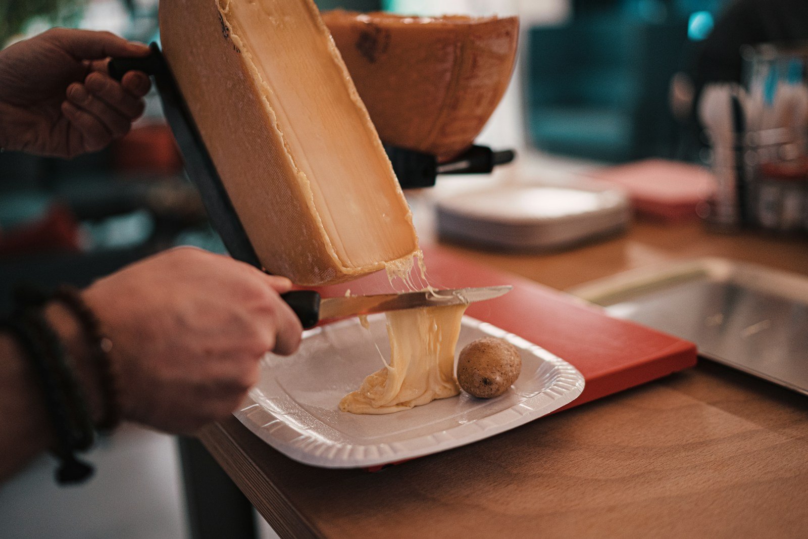 person pouring melted cheese on a plate.