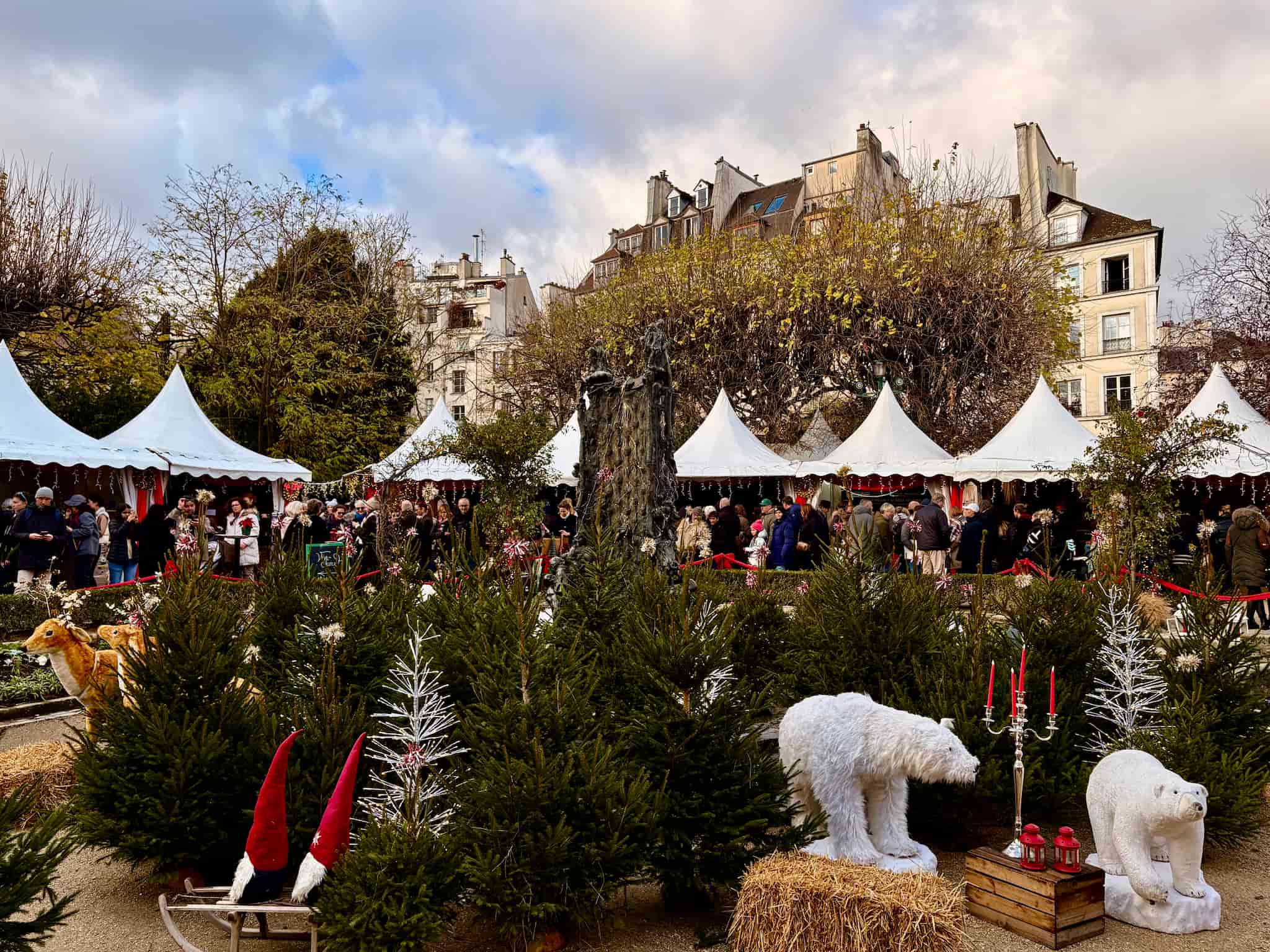 Paris Notre Dame Christmas Market, white tents with booths and Christmas decorations in the center of the park.