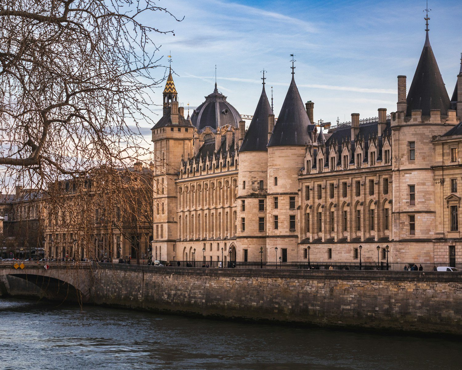 Historic castle on a riverbank with blue sky.