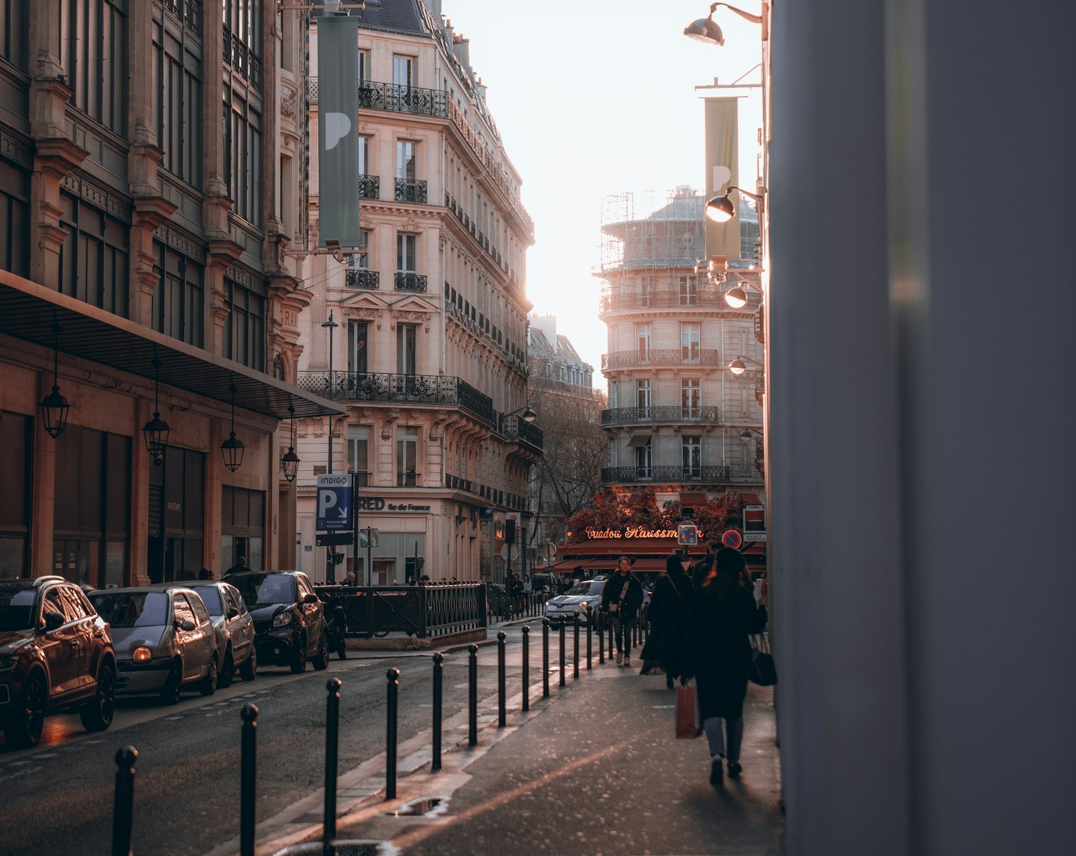a city street lined with tall buildings and parked cars.
