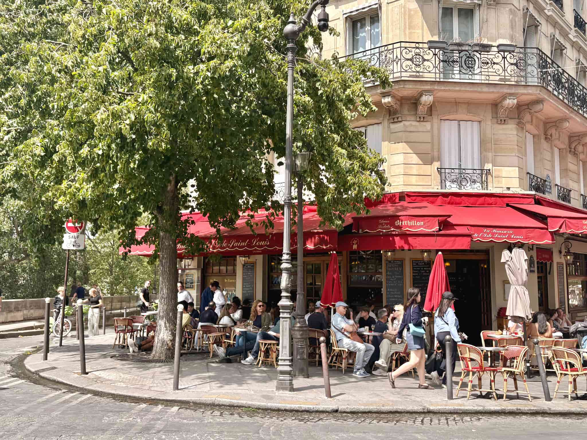 Parisian bistro corner with a red awning and café tables on Île Saint-Louis.