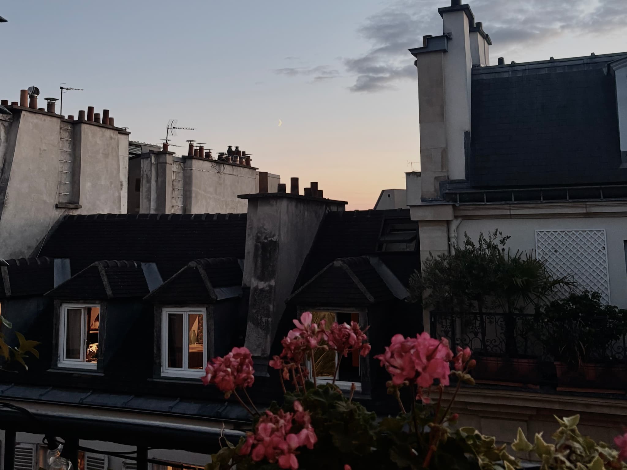 Sunset with a crescent moon visible above Parisian rooftops